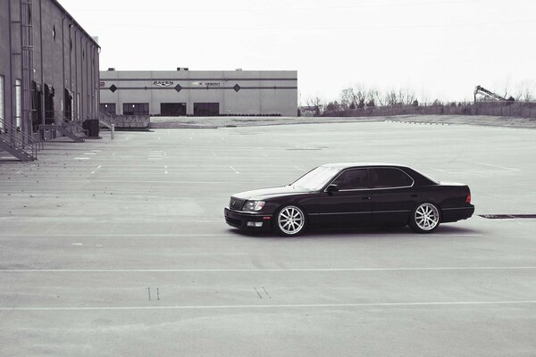 An old Lexus in front of warehouses