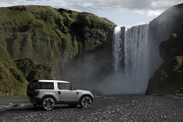 Land rover car on the background of a beautiful waterfall