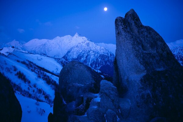 Snow-capped mountains and the moon in the sky