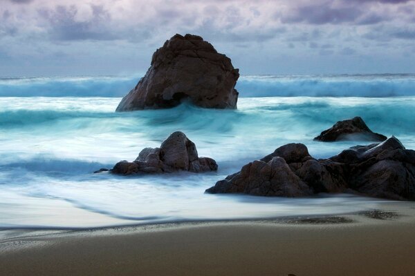 The sea waves are beating against the rocks