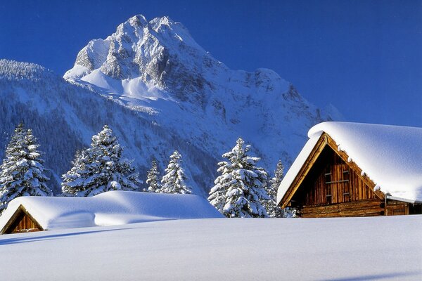 Die Dächer der Häuser im Winter vor dem Hintergrund der majestätischen schneebedeckten Berge