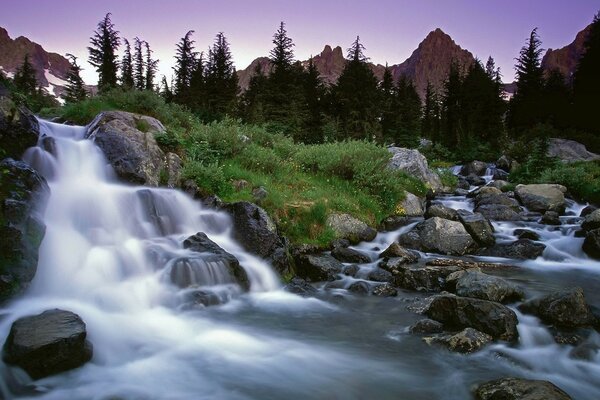 Wasserfall zwischen Steinen und Gras in den Bergen