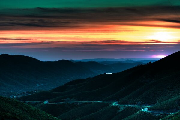 Camino montañoso que sale en una hermosa puesta de sol