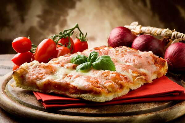 Delicious pizza on a red napkin , with onions and tomatoes on a wooden platter