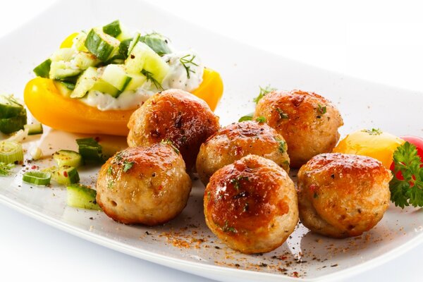 Meatballs with vegetables baked on a white plate