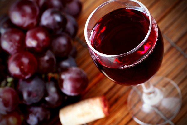 Ein Glas Wein und rote Trauben auf dem Tisch