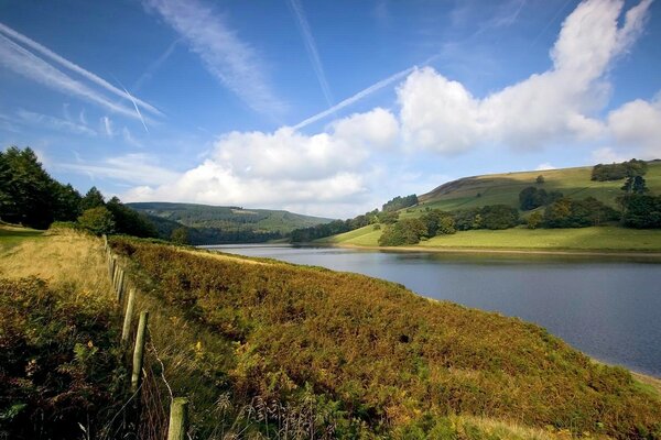 Rustic landscape. The river behind the fence and the clear blue sky