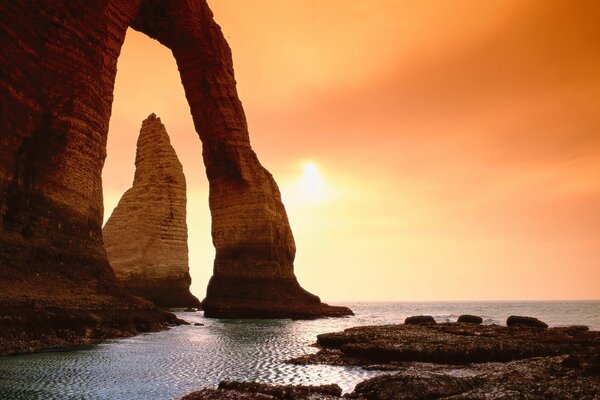 Enormes rocas en la orilla del mar en el fondo de una hermosa puesta de sol