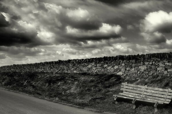 Photographie en noir et blanc avec banc et route
