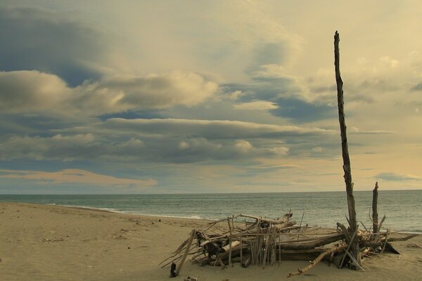 Sur la plage se trouvent les débris derrière la mer et les nuages