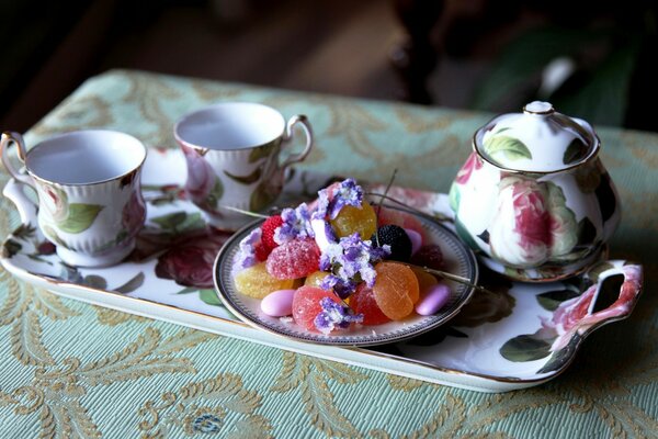 Ensemble de thé en porcelaine sur un beau plateau avec des bonbons sur une assiette