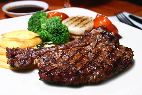 Pork steak on a white plate with vegetables