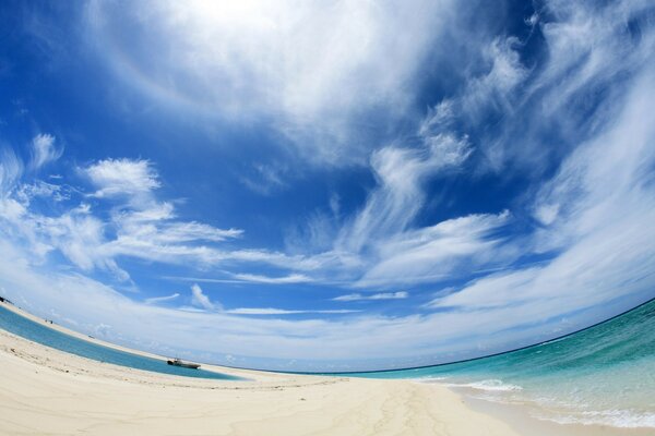 Nubes dispersas cubren agua, arena