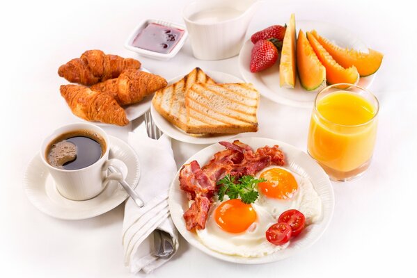 Desayuno con huevos revueltos y cruasanes sobre un fondo blanco