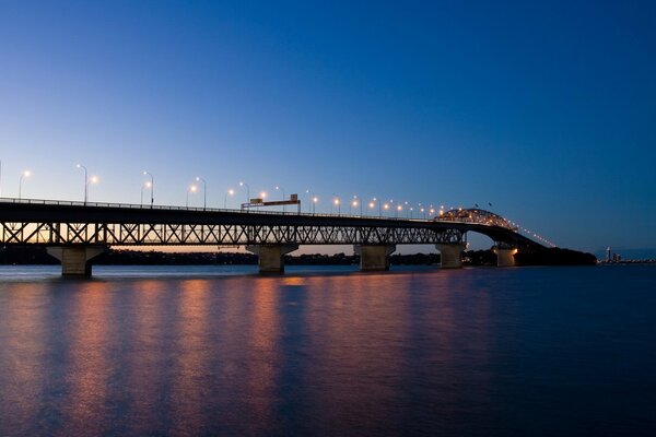 A bridge with evening lights leading to the city