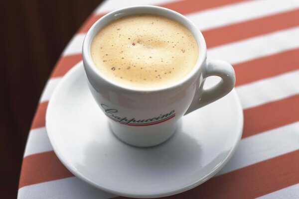 Cappuccino in a white cup on a striped tablecloth