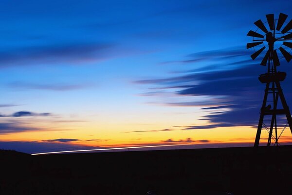 The windmill stands against the background of the evening sunset