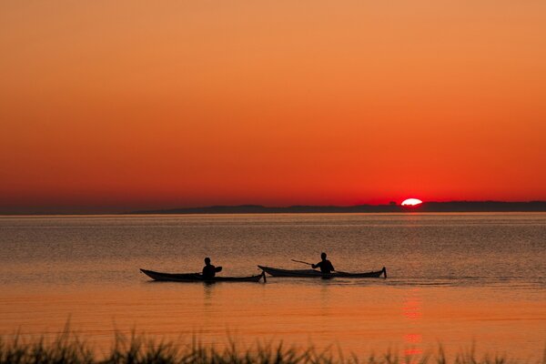 Paisaje con un lago y dos barcos al atardecer