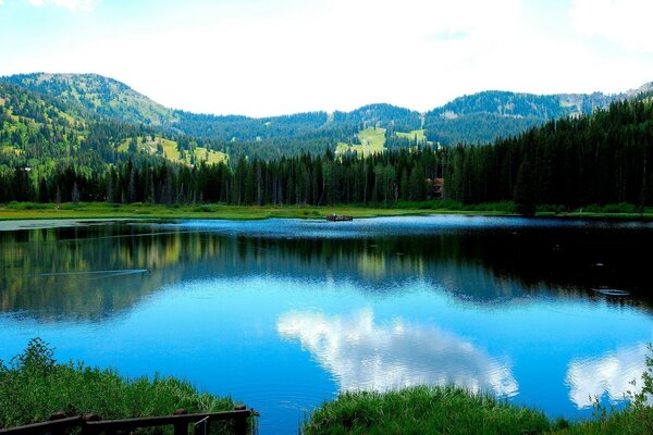 Forest mountains and blue sky are reflected in the lake