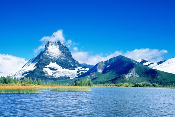 Lago vicino alle montagne. Cielo blu con nuvole bianche