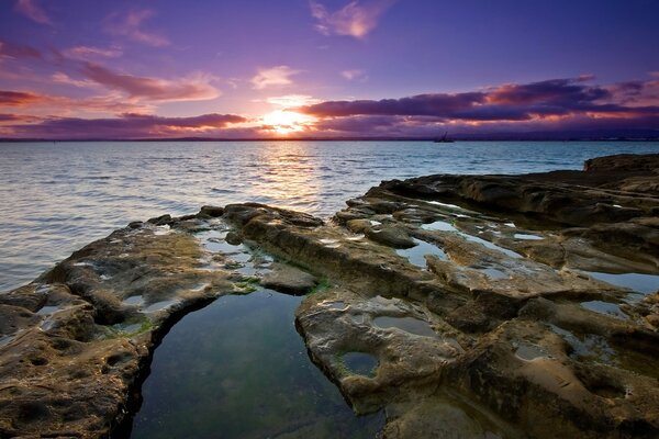 Sunset with a view of the rocky shore and the water surface