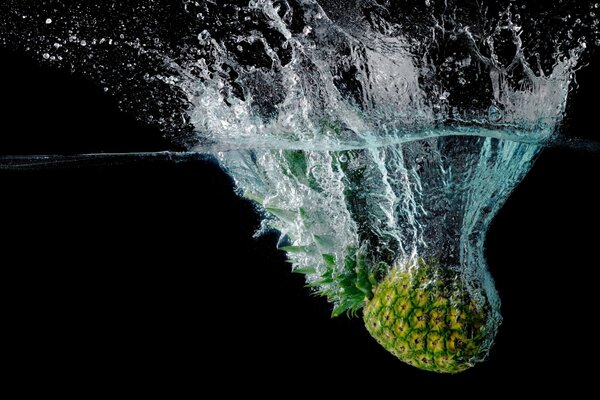 Pineapple fell into the water on a dark background