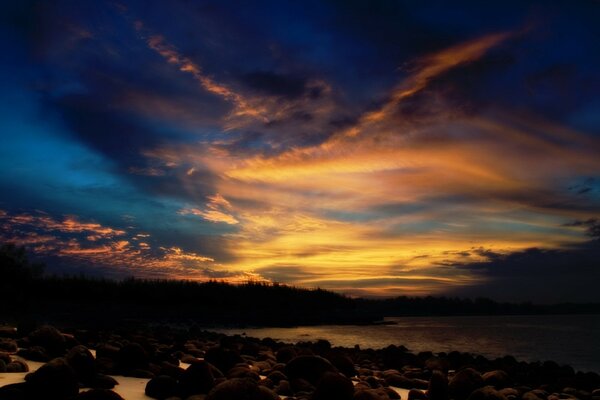 Hermosa puesta de sol junto al agua con piedras