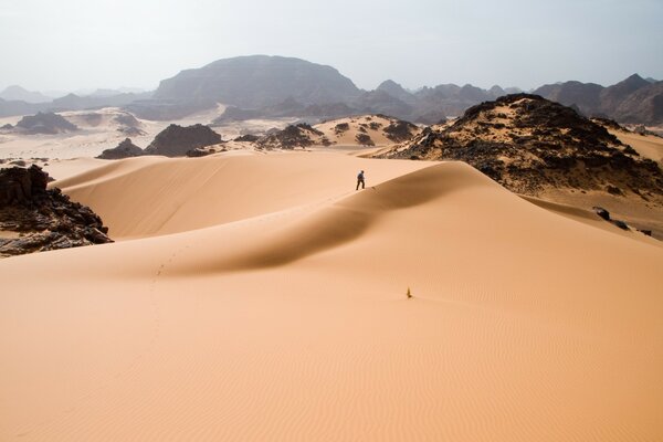 Człowiek na pustyni idzie po piasku