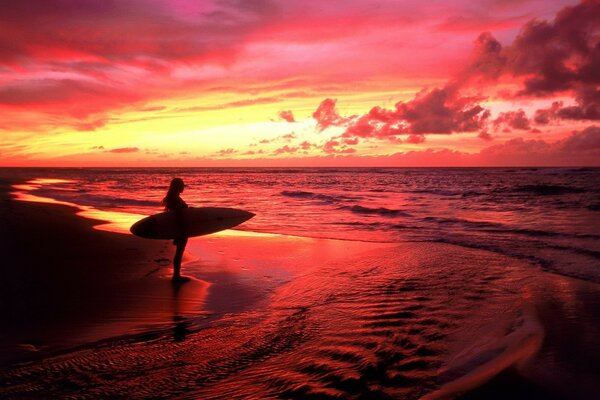 Девушки серфер стоит на закате у моря