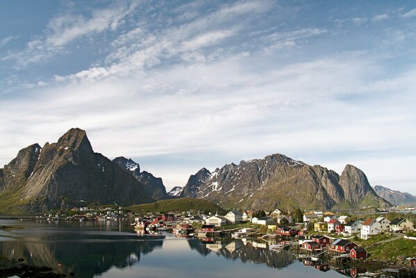 A village by the mountains and water under a blue sky