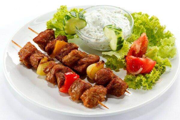 Kebab en brochetas con verduras y salsa