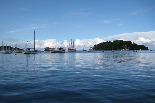 Красивое фото моря, на котором расположен остров и плавают яхты
