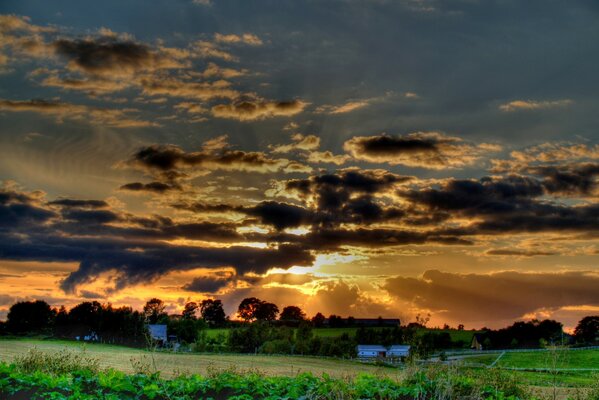 Beaux nuages sur le village et le champ vert