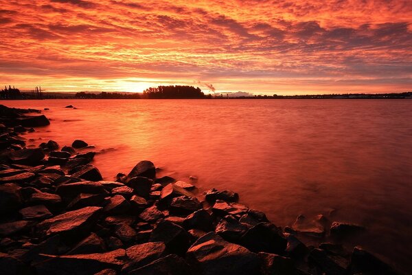 Красный закат. Каменистый берег озера