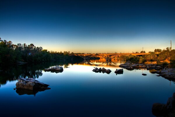 Ponte sul fiume blu nei raggi del tramonto