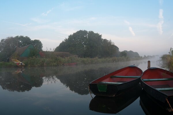 2 boats in the middle of the river in the fog