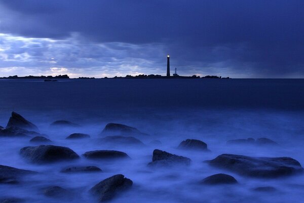 Piedras en la niebla y un faro en la distancia