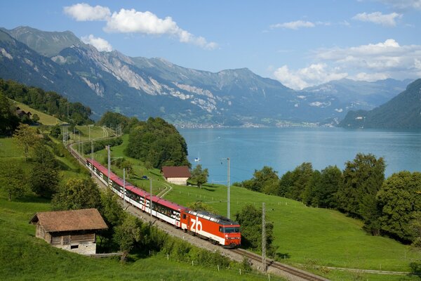 A train running in the mountains along a picturesque river and houses