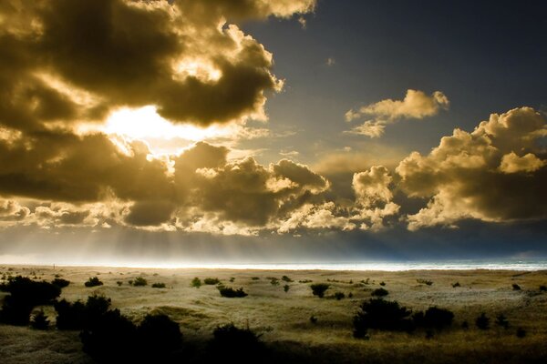 Dunkler Himmel mit Wolken. Die Strahlen der Sonne durch die Wolken. Horizont