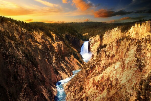 Piękne niebo o zachodzie słońca. Wodospad w skałach Yellowstone