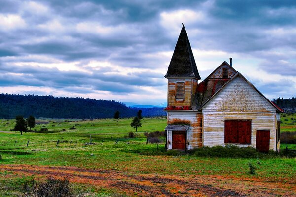 A house in a field with a view of the forest and mountains