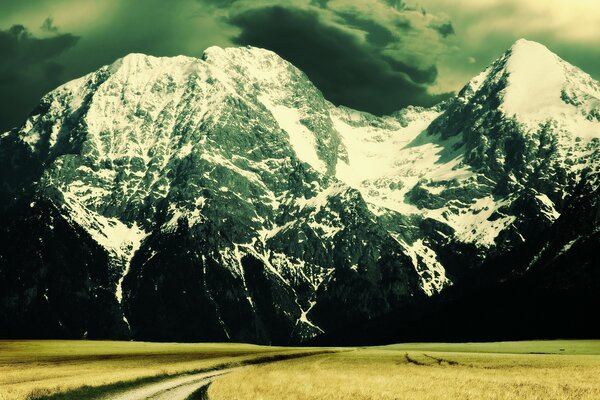 A road in a field against the background of mountains