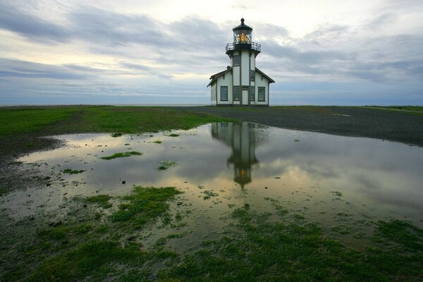 Lighthouse on the shore and puddles