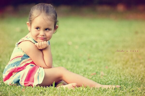 Очаровательная девчушка сидит на травке