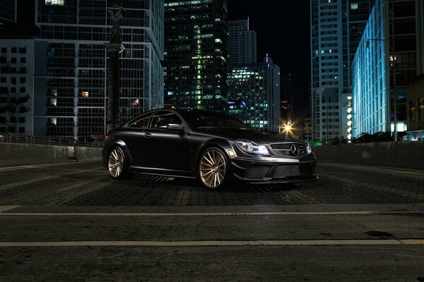 Black Mercedes C class on the background of the night city