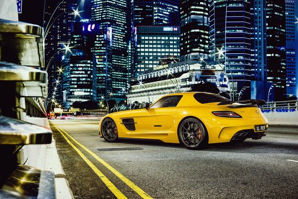 Mercedes amarillo en el fondo de los rascacielos de la ciudad nocturna