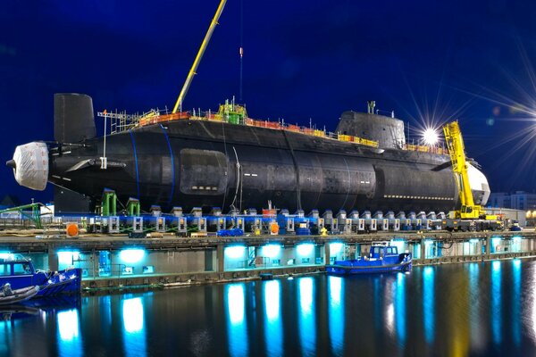 Submarino nuclear en un muelle nocturno iluminado