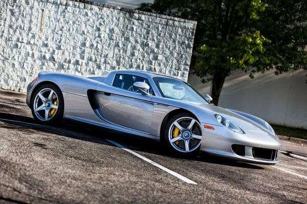 Srebrne Porsche Carrera GT na tle ściany