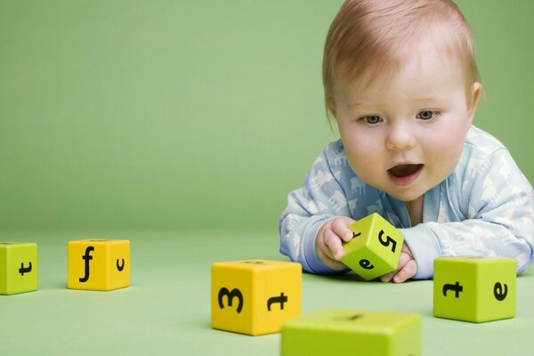 The kid looks at the cubes with interest