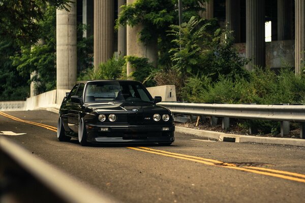 On the highway, a black BMW with extinguished headlights